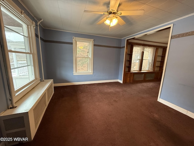 empty room featuring crown molding, radiator heating unit, ceiling fan, and dark carpet