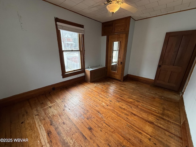 unfurnished room featuring radiator, wood-type flooring, ornamental molding, and ceiling fan