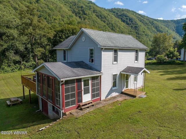 229 River Rd, Renovo, PA 17764 - rear view of house featuring a wooded view, a sunroom, a shingled roof, and a lawn