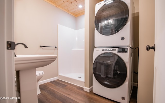 laundry area with wood finished floors, laundry area, wood ceiling, baseboards, and stacked washing maching and dryer