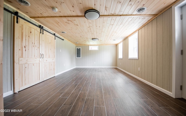 interior space with dark wood finished floors, a barn door, visible vents, and wood ceiling