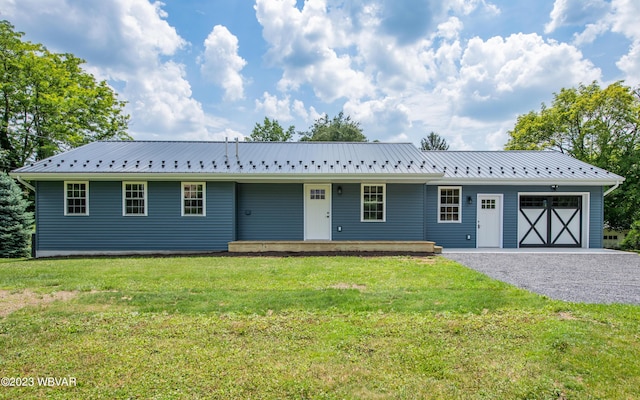 ranch-style home with driveway, metal roof, a front lawn, and a garage