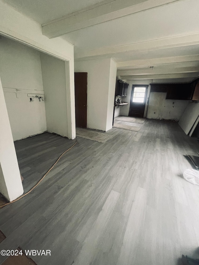 unfurnished living room featuring hardwood / wood-style floors and beam ceiling