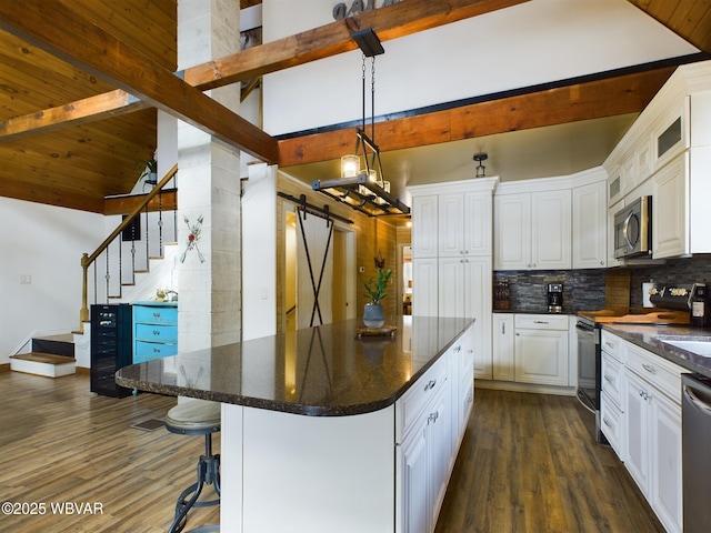 kitchen with white cabinetry, appliances with stainless steel finishes, a barn door, and decorative light fixtures