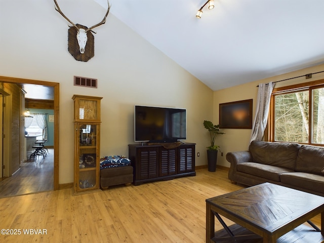 living room featuring high vaulted ceiling and light hardwood / wood-style floors