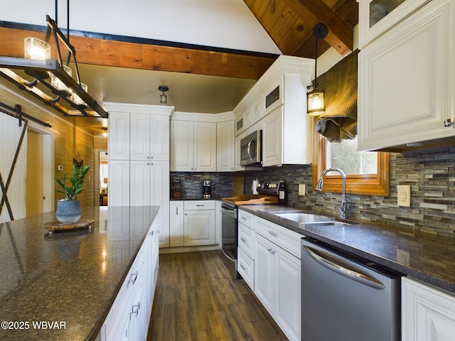 kitchen with sink, hanging light fixtures, stainless steel appliances, a barn door, and white cabinets