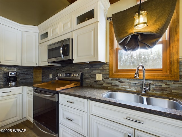 kitchen featuring sink, white cabinetry, hanging light fixtures, stainless steel appliances, and decorative backsplash