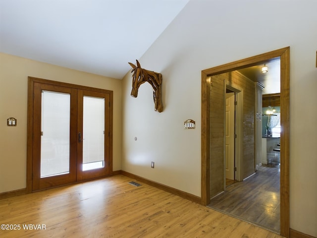 doorway with vaulted ceiling, light hardwood / wood-style floors, and french doors