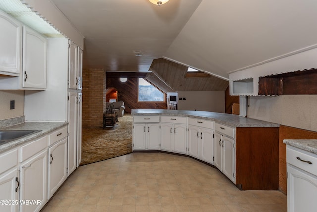 kitchen with white cabinetry, kitchen peninsula, vaulted ceiling, and light carpet