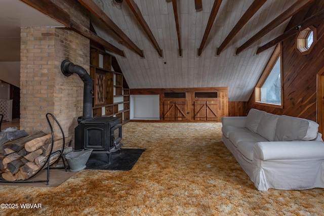 unfurnished living room featuring vaulted ceiling with beams, carpet, wood walls, and a wood stove