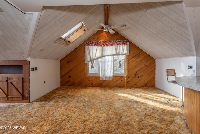 bonus room featuring ceiling fan, vaulted ceiling with skylight, carpet, and wood walls