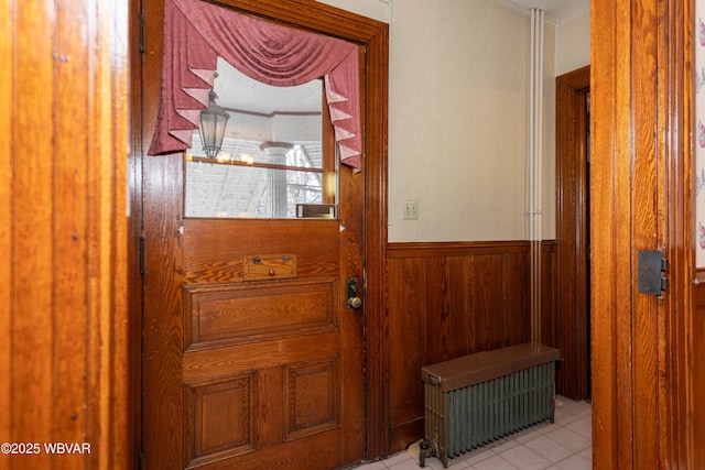 entryway featuring light tile patterned flooring, wooden walls, and radiator