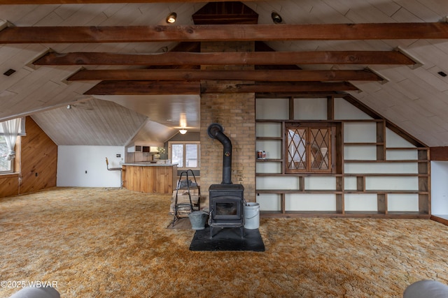 interior space featuring vaulted ceiling with beams, a wood stove, wood walls, and carpet