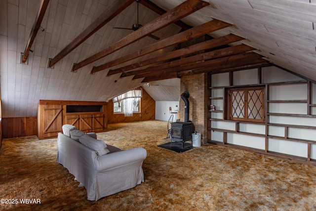 interior space featuring carpet floors, a wood stove, lofted ceiling with beams, and wood walls