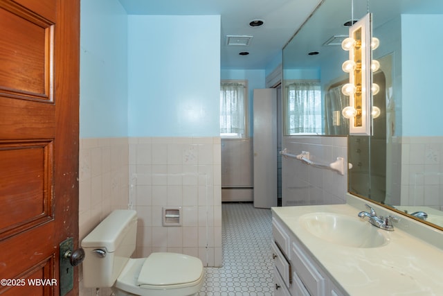 bathroom featuring tile walls, vanity, toilet, and a baseboard heating unit