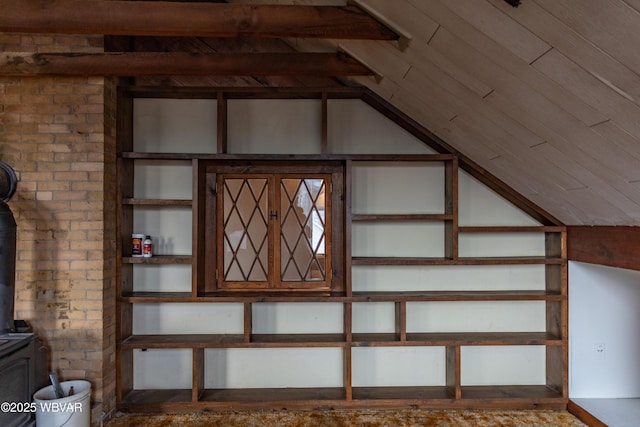 interior space with brick wall, lofted ceiling, and a wood stove