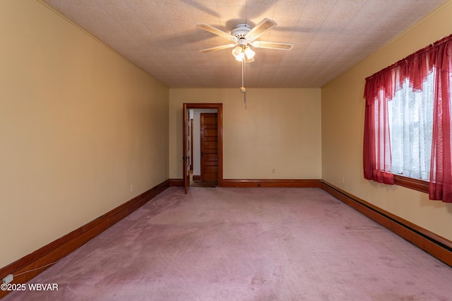 carpeted empty room featuring a baseboard heating unit and ceiling fan