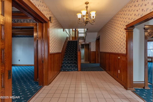 hallway featuring a notable chandelier, wooden walls, and light tile patterned flooring