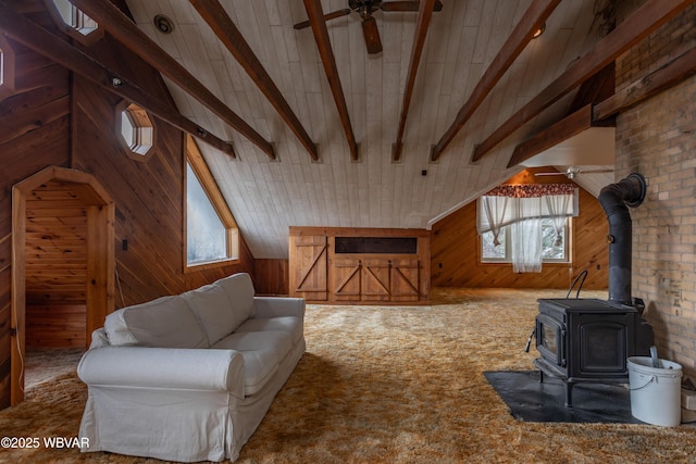 living room featuring lofted ceiling with beams, carpet, a wood stove, and wood walls