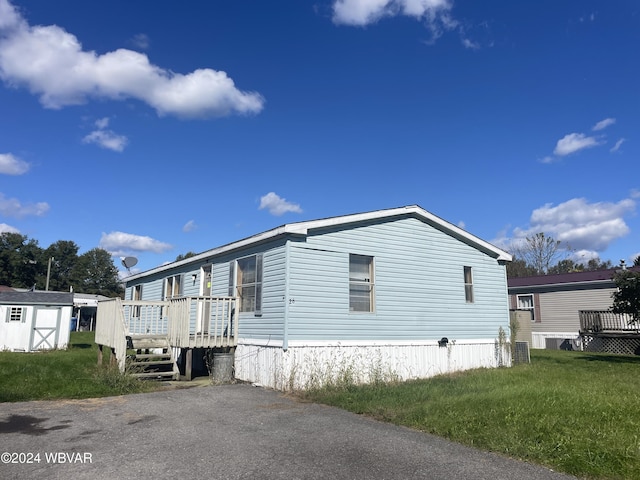 view of home's exterior with a yard, a storage unit, and a wooden deck