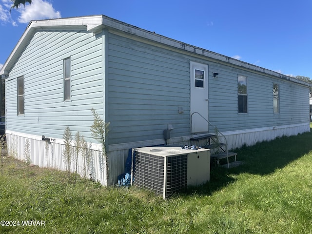 back of house featuring a lawn and central AC unit