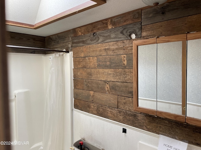 bathroom featuring wood walls and walk in shower