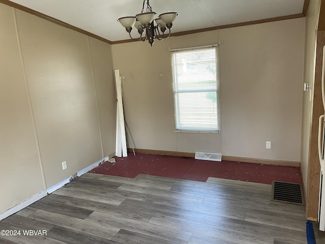 spare room featuring hardwood / wood-style floors, an inviting chandelier, and crown molding