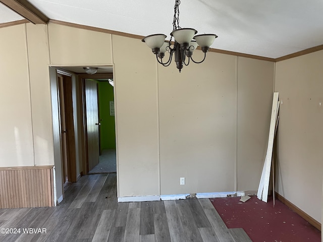 unfurnished dining area with dark hardwood / wood-style flooring, ornamental molding, lofted ceiling, and an inviting chandelier