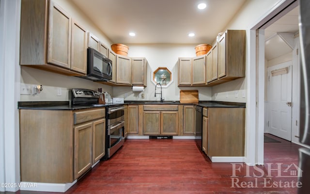 kitchen featuring dark wood-style floors, dark countertops, recessed lighting, a sink, and black appliances