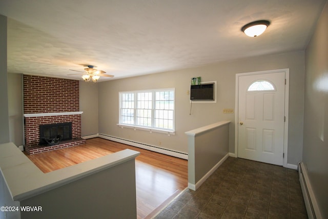 foyer entrance featuring dark hardwood / wood-style floors, ceiling fan, baseboard heating, and a brick fireplace