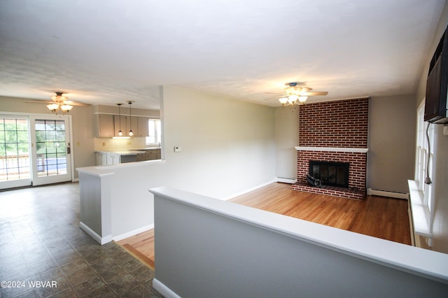 unfurnished living room with a fireplace, dark hardwood / wood-style flooring, ceiling fan, and a baseboard heating unit