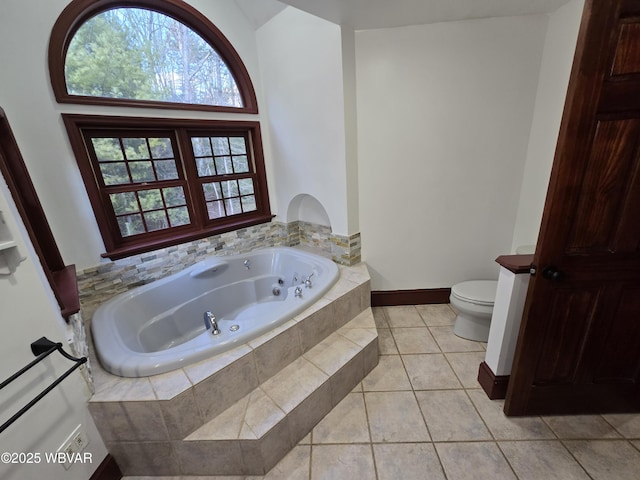 full bath with tile patterned floors, toilet, a tub with jets, and baseboards