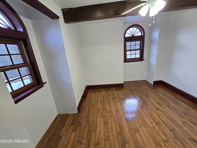 unfurnished room with beamed ceiling, baseboards, hardwood / wood-style floors, and a ceiling fan