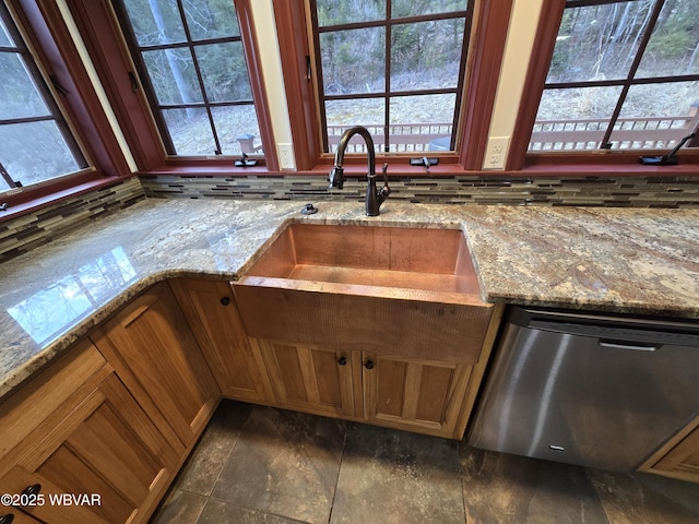 kitchen featuring a sink, light stone countertops, dishwasher, and brown cabinetry