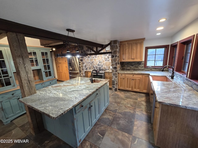 kitchen featuring a sink, stone finish flooring, light stone counters, and backsplash