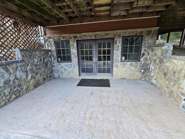 entrance to property featuring stone siding, french doors, and a patio