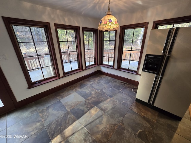 unfurnished dining area featuring stone finish flooring and baseboards