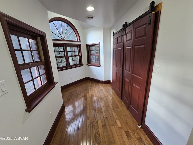 hallway with visible vents, dark wood-style floors, recessed lighting, a barn door, and baseboards