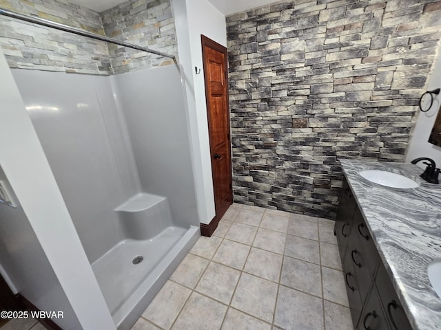 full bathroom featuring a sink, double vanity, a shower stall, and tile patterned floors