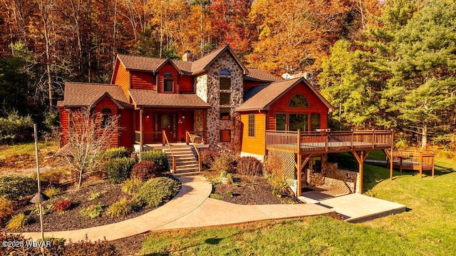 log home with a shingled roof, a front lawn, a wooden deck, a chimney, and stone siding