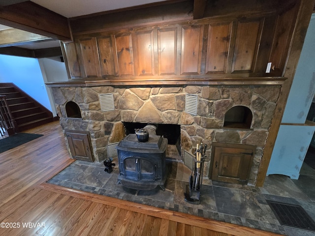 interior details featuring a wood stove, wood finished floors, and visible vents