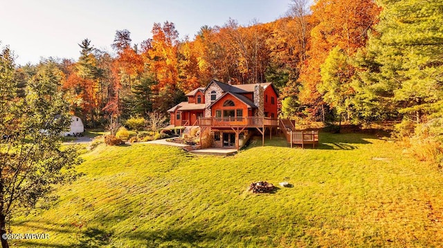 rear view of property featuring a wooden deck, a view of trees, a yard, and stairs