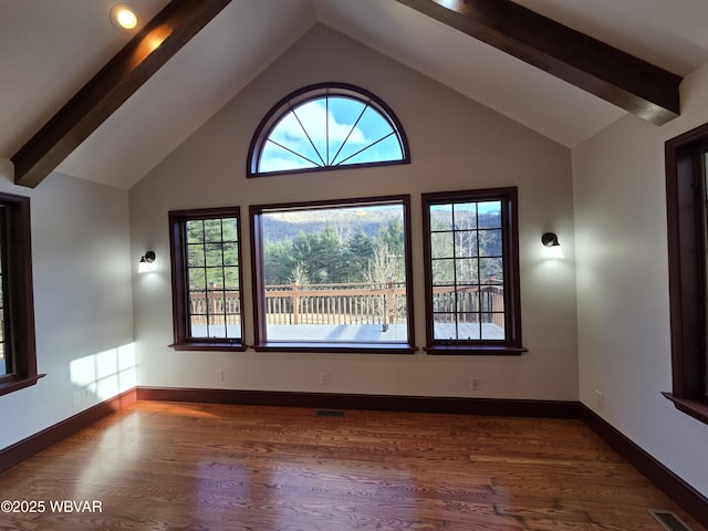 empty room featuring beam ceiling, wood finished floors, and visible vents