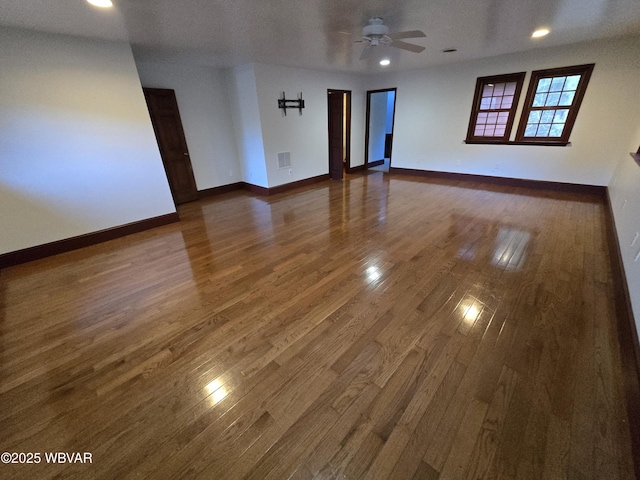 unfurnished room featuring hardwood / wood-style flooring, a ceiling fan, baseboards, and visible vents