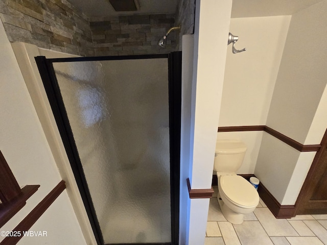 bathroom featuring tile patterned floors, toilet, and a shower stall