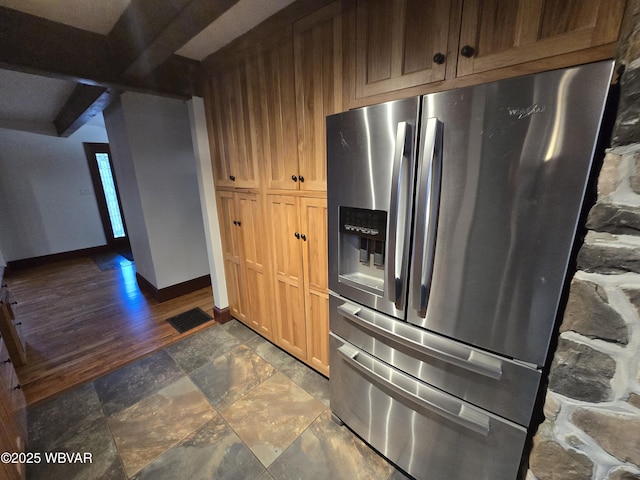 kitchen with beam ceiling, stainless steel fridge, stone finish floor, and baseboards