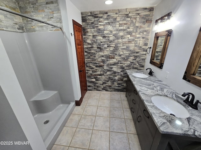 bathroom featuring tile patterned floors, a shower stall, double vanity, and a sink