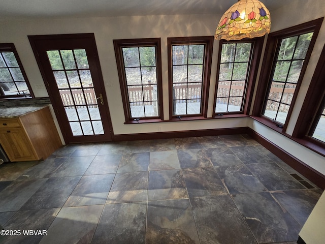 unfurnished dining area featuring visible vents, baseboards, a healthy amount of sunlight, and stone finish flooring