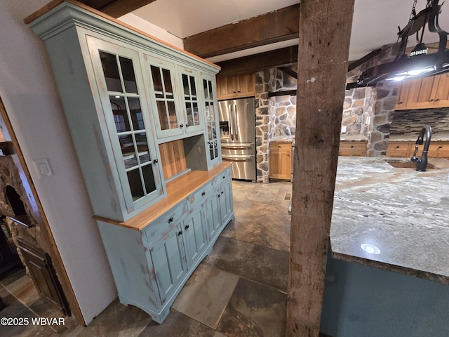 kitchen featuring beamed ceiling, stone finish floor, a sink, butcher block counters, and stainless steel fridge with ice dispenser