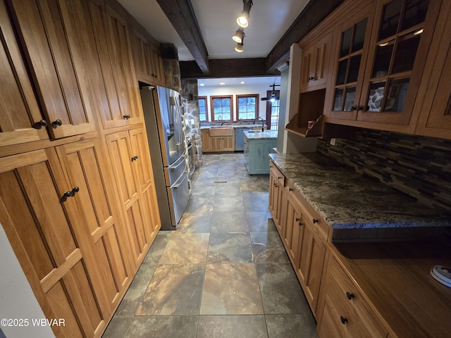 kitchen with glass insert cabinets, beamed ceiling, appliances with stainless steel finishes, a peninsula, and stone countertops